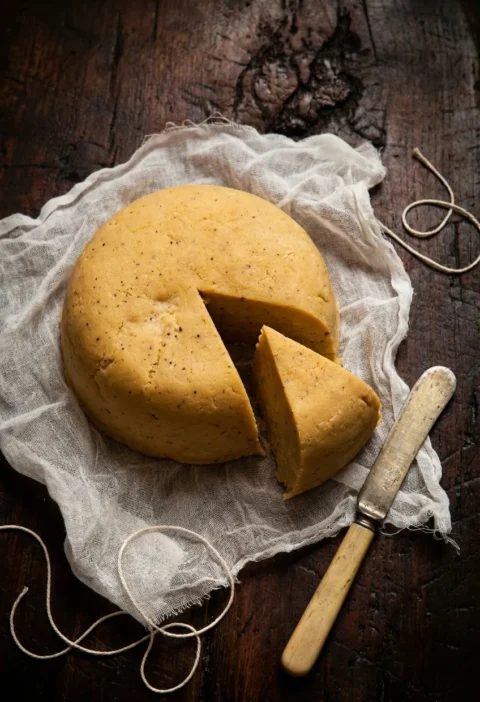 Pease pudding dome with wedge cut on muslin cloth showing dense golden yellow interior with pepper flecks