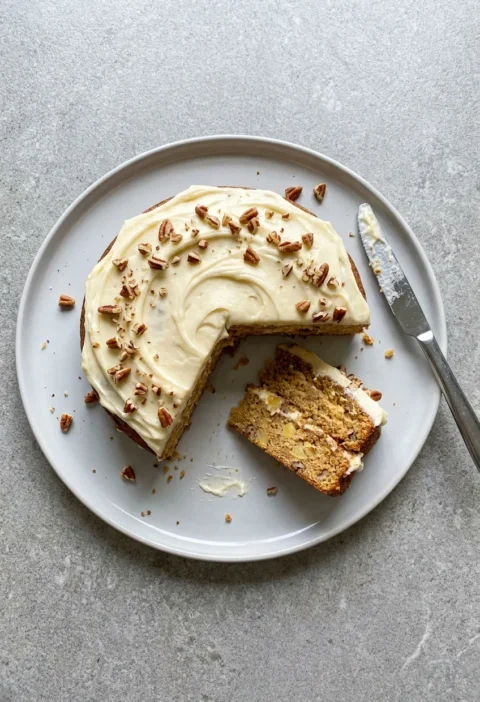 Hairy Bikers banana and pineapple cake with cream cheese icing and pecans, one slice cut showing two sponge layers