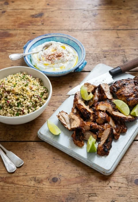 Hairy Bikers chicken shawarma sliced on a board with lime, labneh and herby couscous