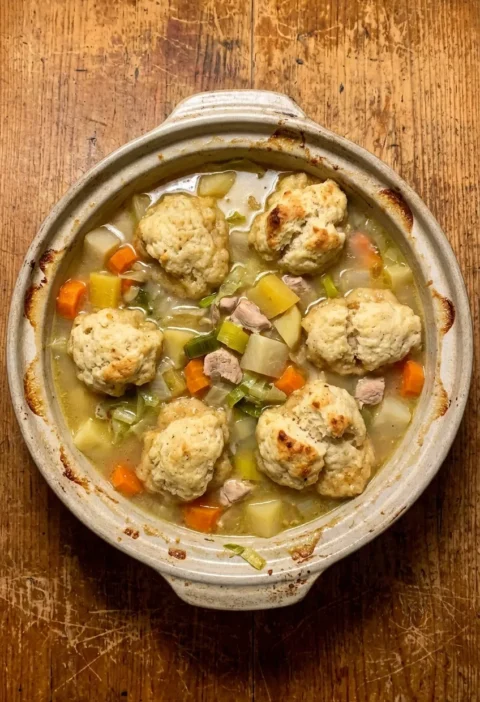 Chicken and dumpling stew with risen suet dumplings over a brothy root vegetable and chicken casserole