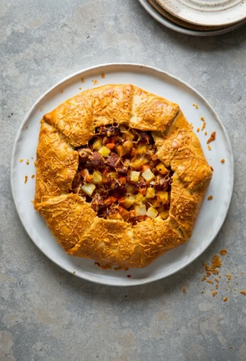 Hairy Bikers corned beef hash pie, a golden free-form galette with folded shortcrust edges and a cheddar crust over a corned beef, swede, carrot and potato filling