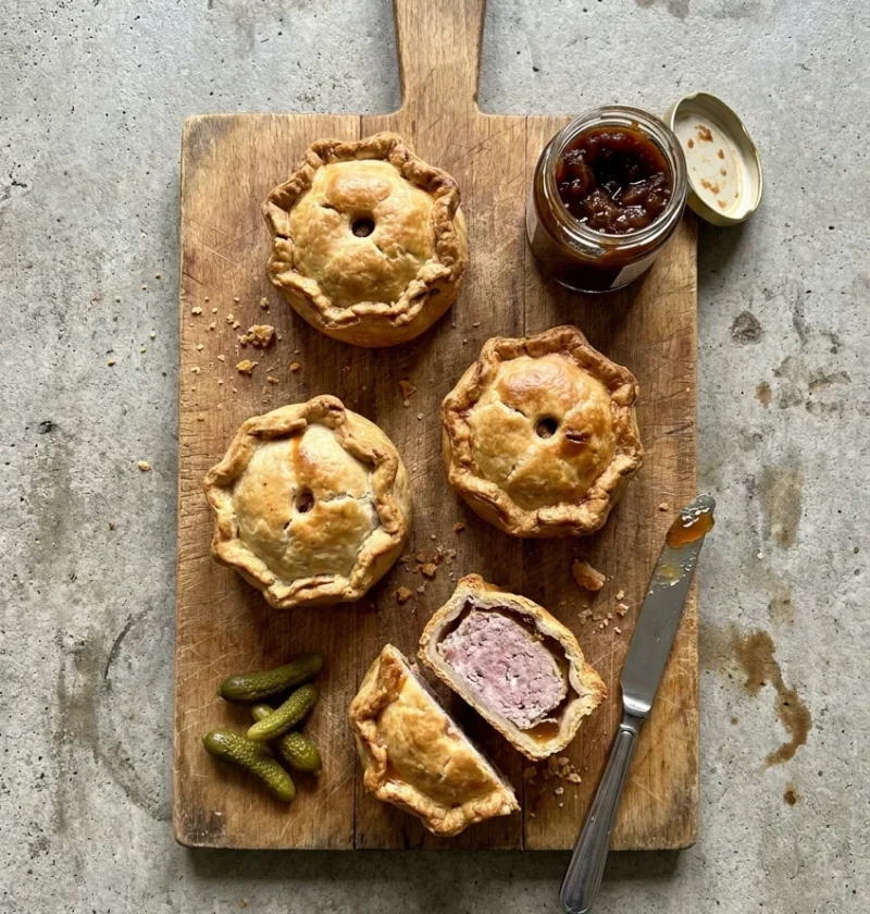 Hairy Bikers pork pie batch of four hand raised pies with one cut open showing the pork filling and amber jelly layer