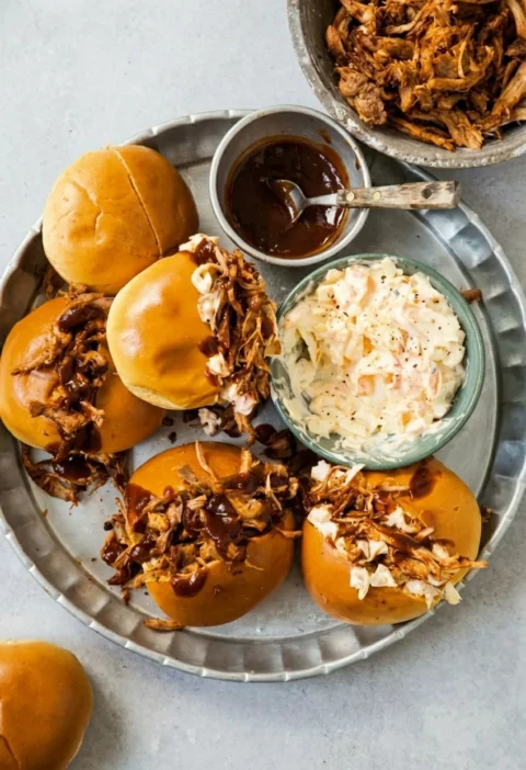 Hairy Bikers bbq pulled pork piled into soft rolls with barbecue sauce and coleslaw, on a metal platter