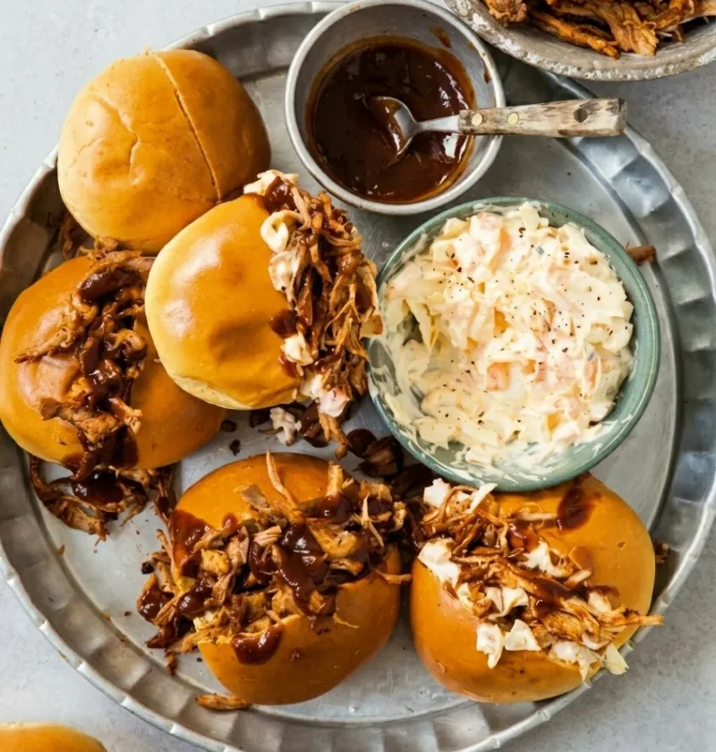 Hairy Bikers bbq pulled pork piled into soft rolls with barbecue sauce and coleslaw, on a metal platter
