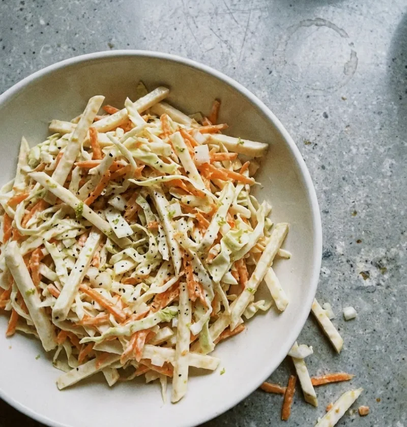 Hairy Bikers coleslaw in a cream bowl with celeriac matchsticks, shredded cabbage and grated carrot in a thin buttermilk dressing