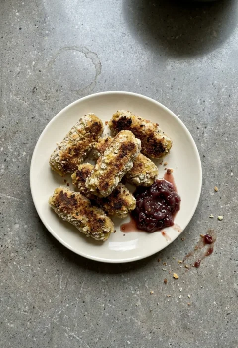 Hairy Bikers Glamorgan sausages on a plate, coated in fresh breadcrumbs and fried golden, served with red onion and chilli relish