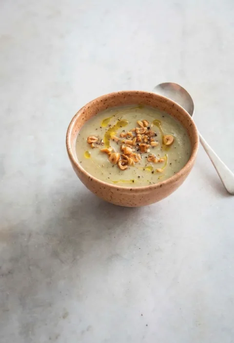Hairy Bikers Jerusalem artichoke soup in a terracotta bowl topped with crushed toasted hazelnuts and a drizzle of oil