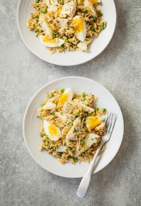 Hairy Bikers kedgeree on two grey plates, curried basmati rice with flakes of smoked haddock, quartered boiled eggs and peas