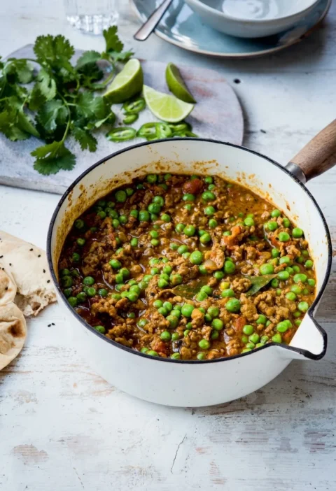 Hairy Bikers keema peas in a cream enamel pan, minced lamb curry with bright green peas, tomato and a bay leaf