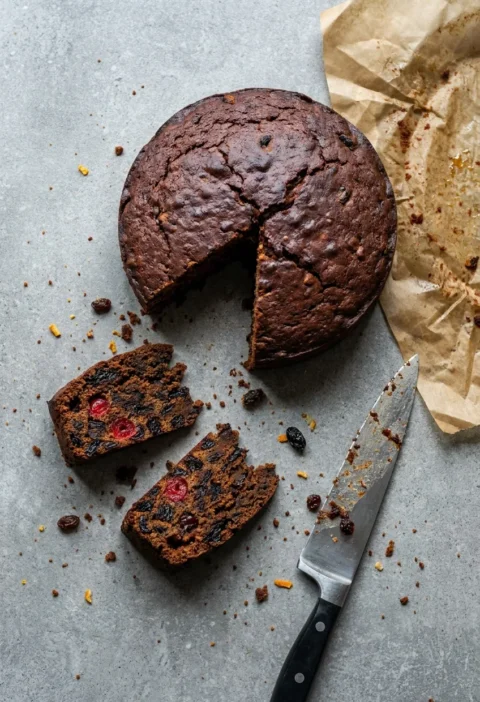 Hairy Bikers boiled fruit cake cut into slices, dark crumb packed with cherries and raisins