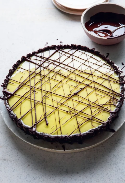A key lime pie with a dark Oreo base and dark chocolate drizzled in lines across a green lime glaze