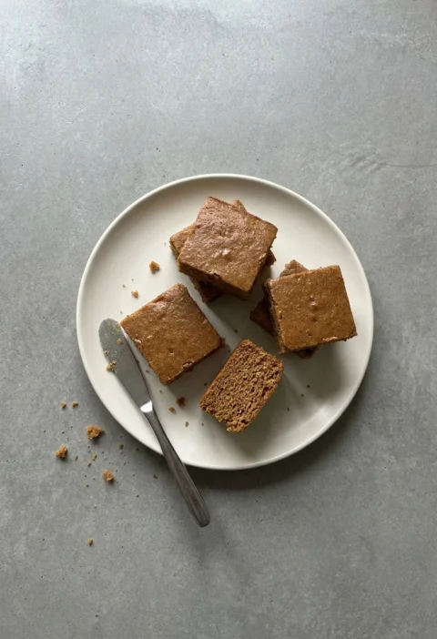 Squares of parkin on a cream plate with a knife resting alongside