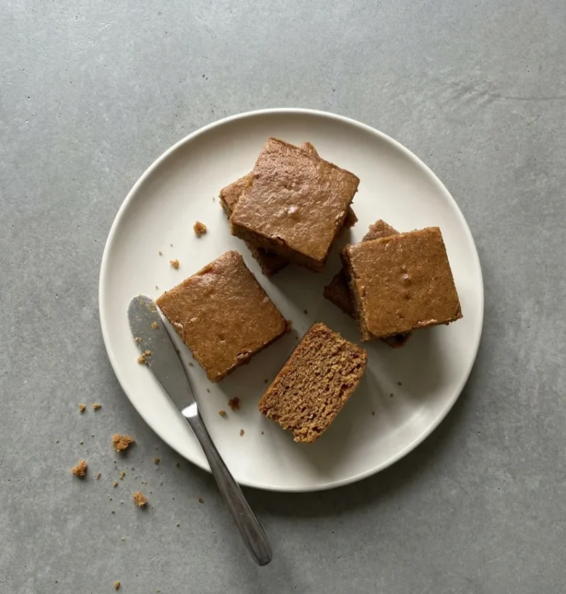 Squares of parkin on a cream plate with a knife resting alongside
