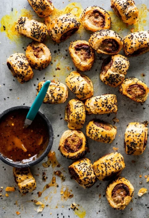 Hairy Bikers sausage rolls on a white plate, cut ends showing vindaloo paste between pastry and sausage meat