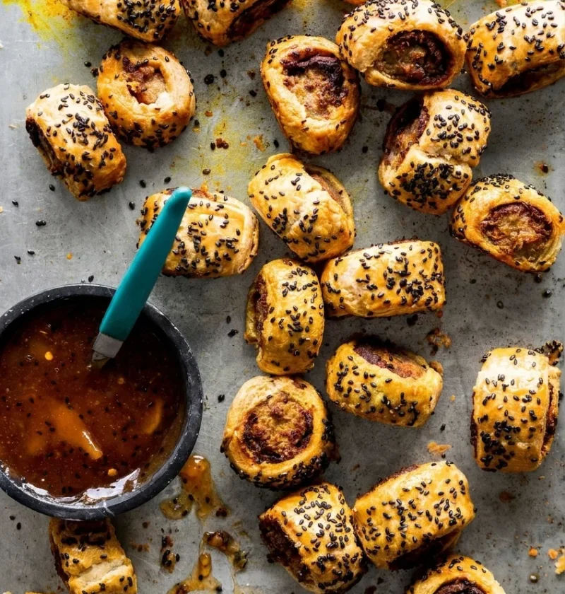 Hairy Bikers sausage rolls on a white plate, cut ends showing vindaloo paste between pastry and sausage meat