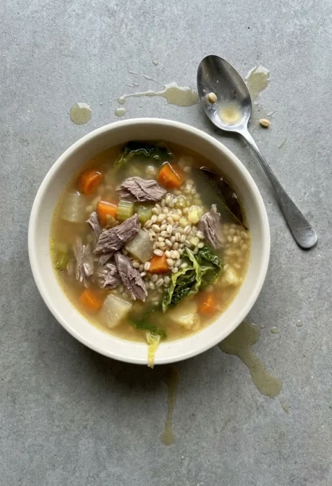Bowl of scotch broth with torn lamb, pearl barley, carrot, turnip and shredded Savoy cabbage