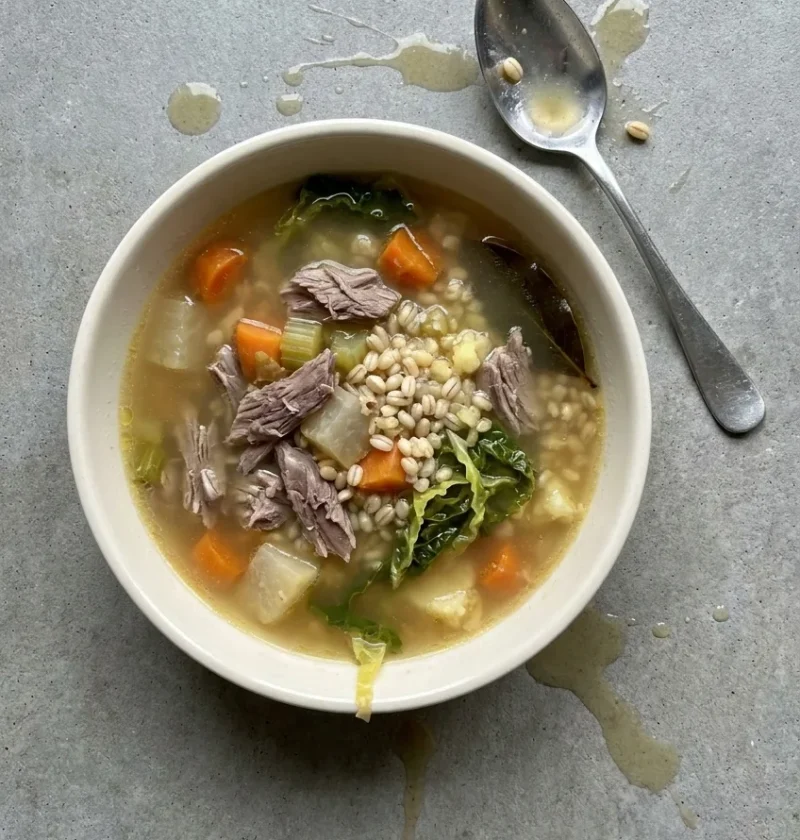 Bowl of scotch broth with torn lamb, pearl barley, carrot, turnip and shredded Savoy cabbage